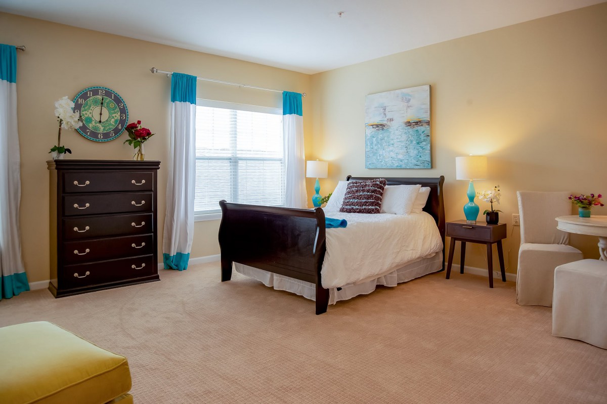 A well-decorated bedroom featuring a large bed, stylish curtains, and ambient lighting.