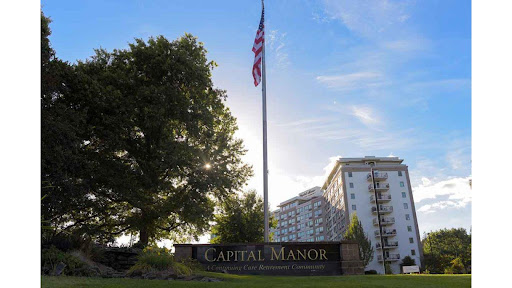 A view of Capital Manor, featuring the American flag against a backdrop of sunlight and residential buildings.