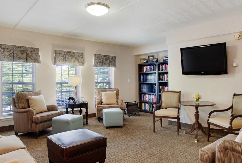 A cozy living room with comfortable seating, a television on the wall, and a bookshelf filled with books.