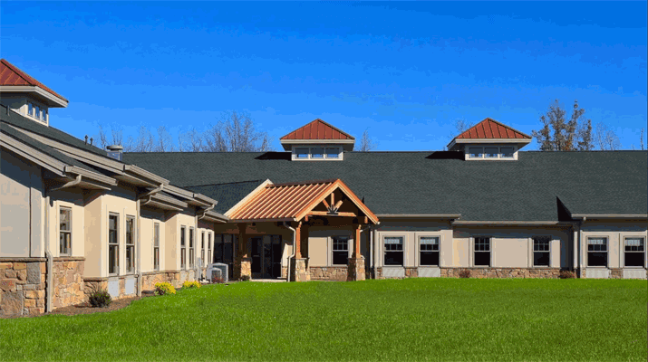 A modern building with a pitched roof and a landscaped lawn under a clear blue sky.