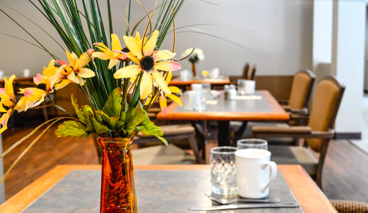 A beautifully set dining table with a vase of flowers.