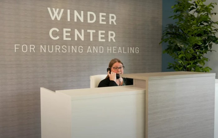 A receptionist at the Winder Center for Nursing and Healing sits behind a desk, speaking on the phone.