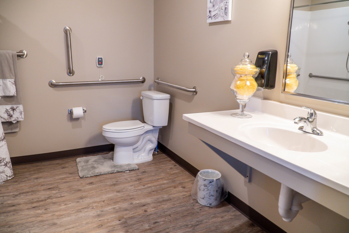 A clean and accessible bathroom with modern amenities and safety handrails.