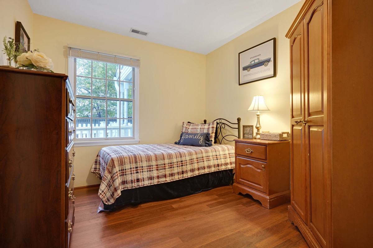 A cozy bedroom with a single bed and wooden furniture.