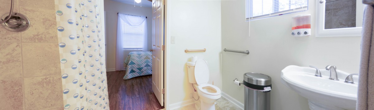 A small bathroom with a toilet and safety rails, adjacent to a bedroom.