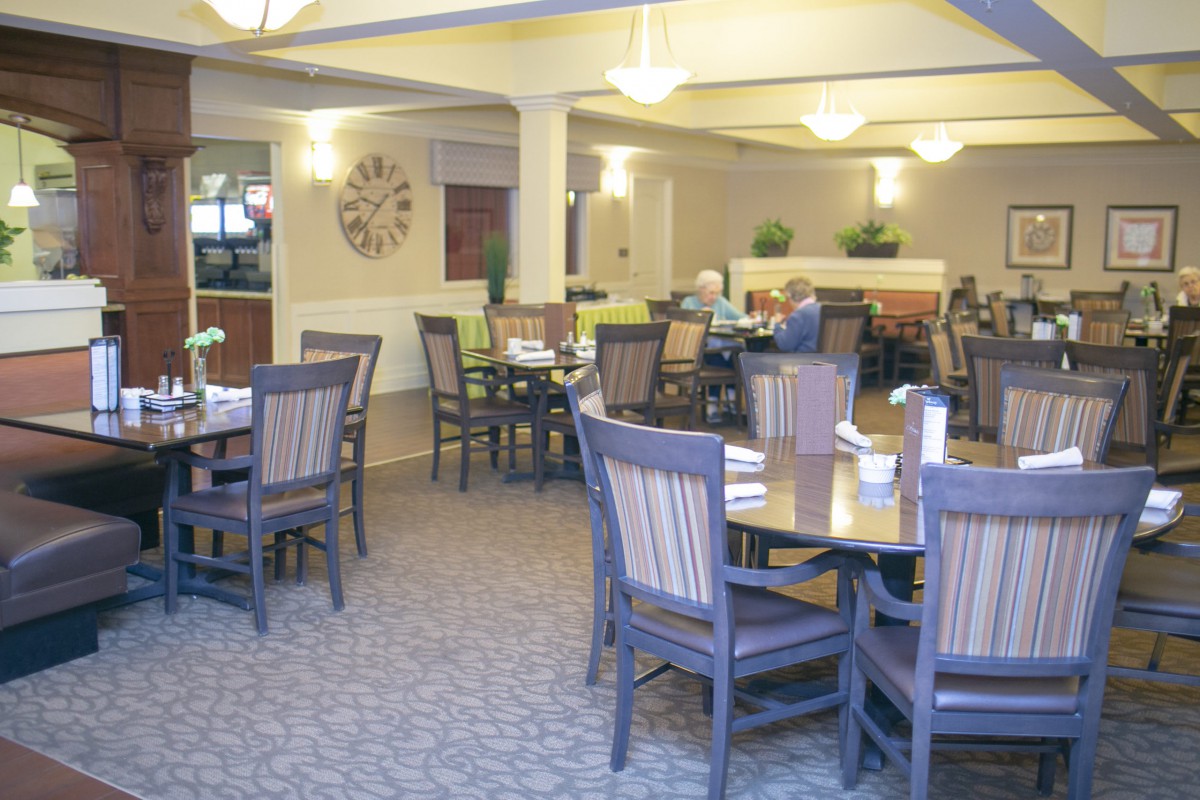 A cozy dining area with several tables and chairs, where people are enjoying their meals.