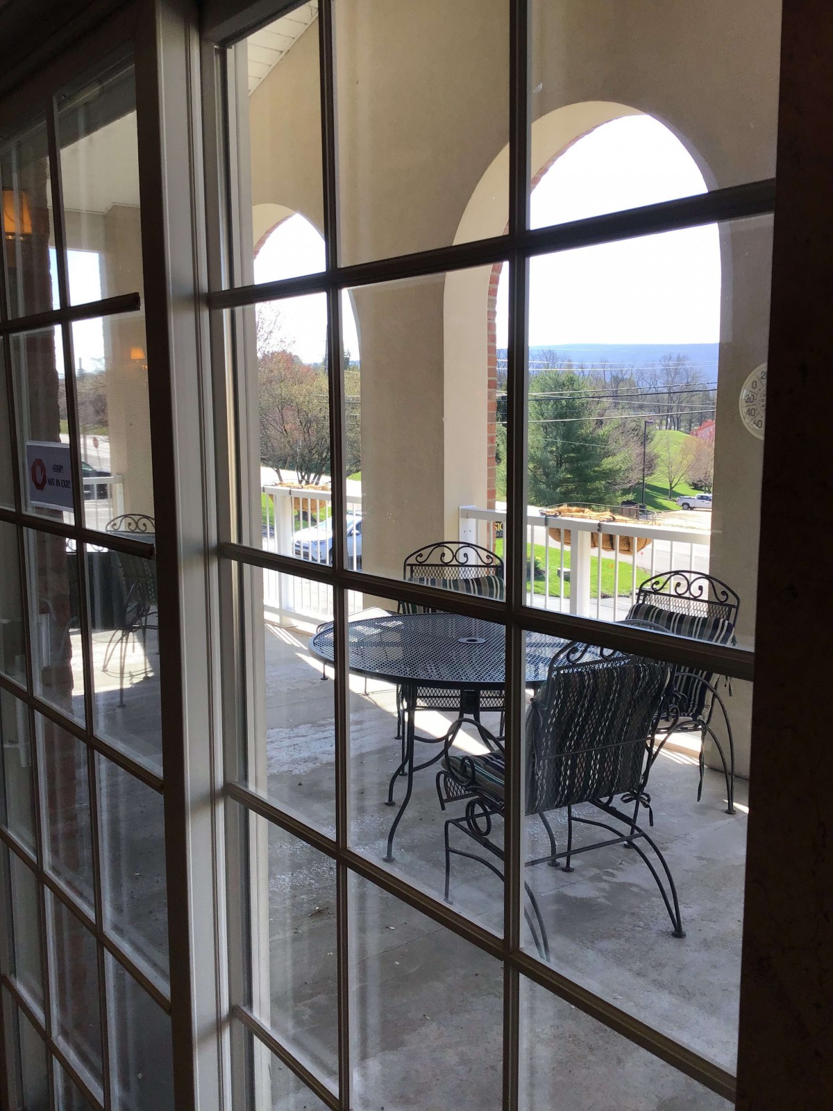 A view of the outdoor patio with a table and chairs through a window.