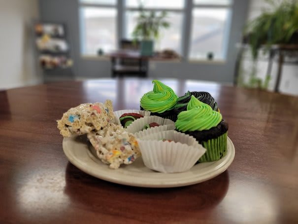 A plate of delicious cupcakes with vibrant green frosting alongside other sweet treats.