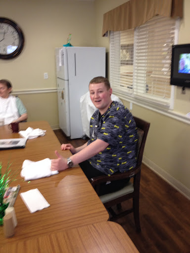 A cheerful gathering at a dining table, with one person smiling for the camera.
