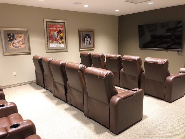 A cozy home theater with rows of comfortable recliners and classic movie posters on the walls.