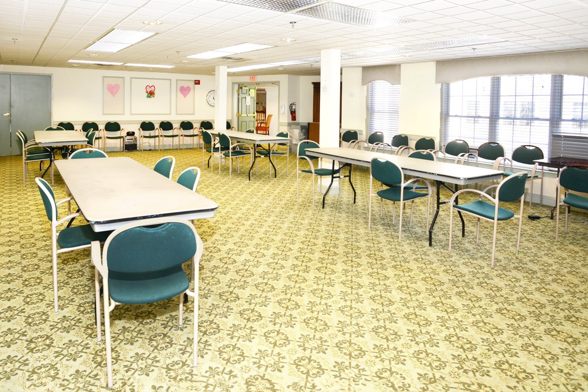 A spacious conference room with arranged tables and chairs, ready for a meeting.