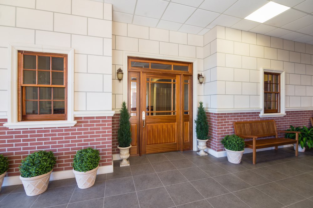 A well-designed entrance with a wooden door and potted plants against a brick wall.