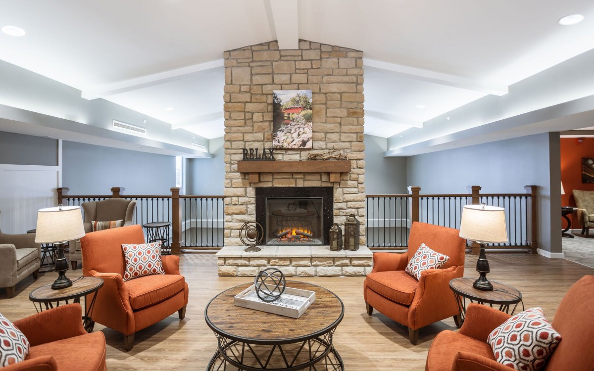 Cozy living room with a stone fireplace and orange armchairs.