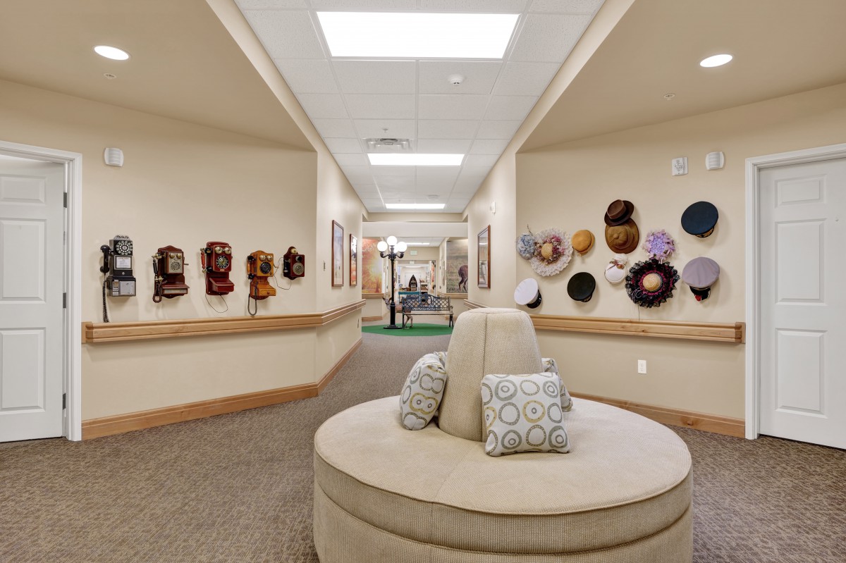 A well-lit hallway with decorative masks on the walls and cushioned seating in the center.