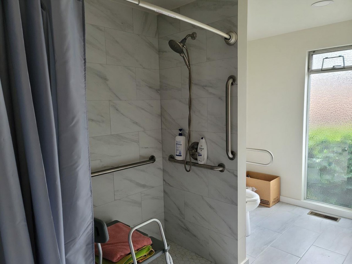 An accessible shower equipped with grab bars and a shower chair.