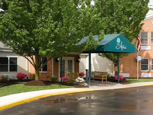 A building entrance with an awning surrounded by trees and landscaping.