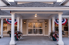 The entrance of a building with columns, decorated with plants and flags.