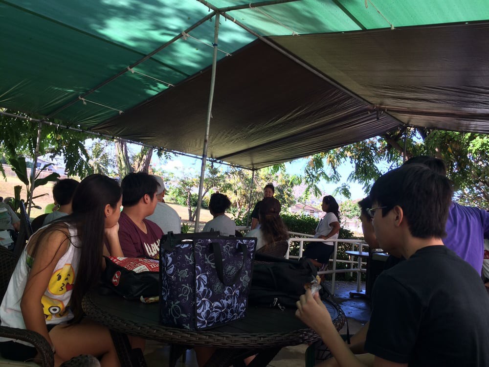 A group of people gathered under a shaded area outdoors.