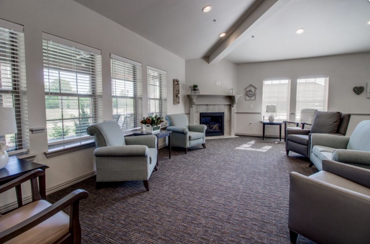 A cozy living room with ample seating, large windows, and a fireplace.