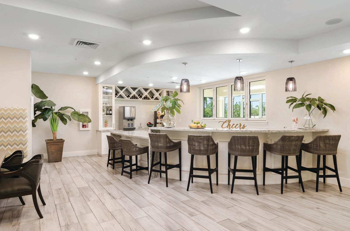 A modern kitchen with bar seating, pendant lighting, and wood flooring.
