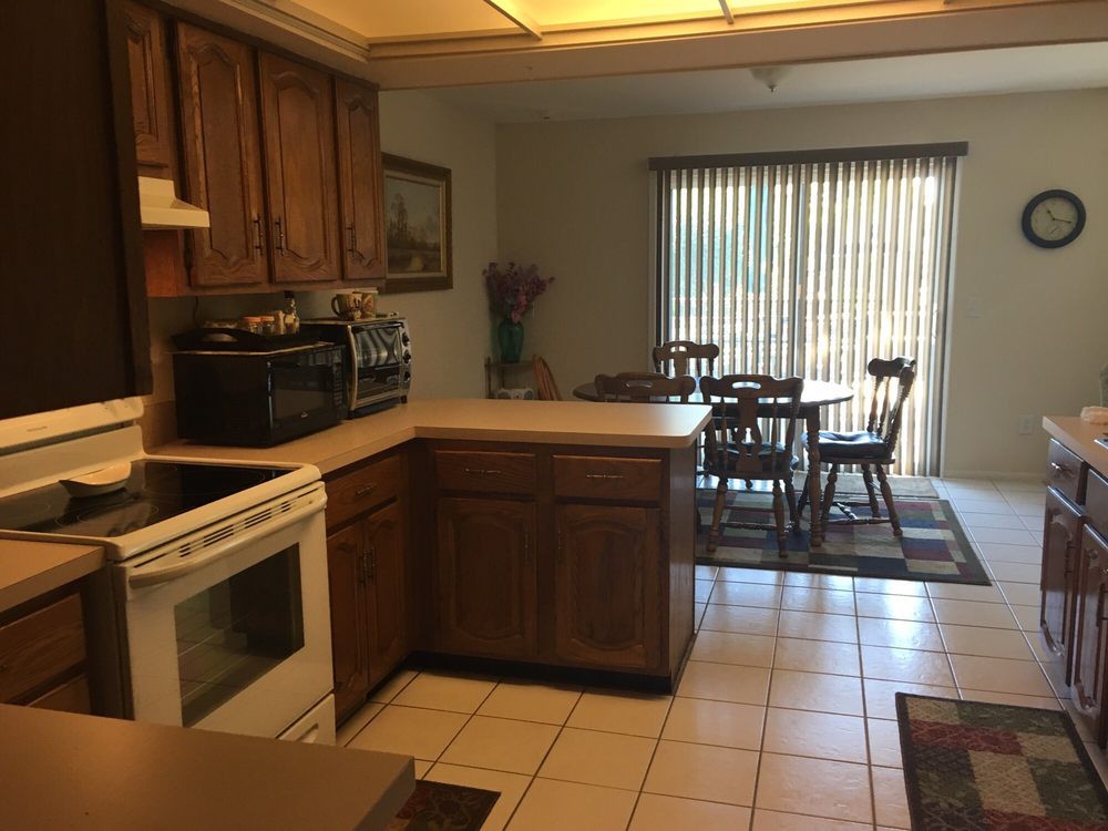 A kitchen with wood cabinets leads into a dining area with a table and chairs.