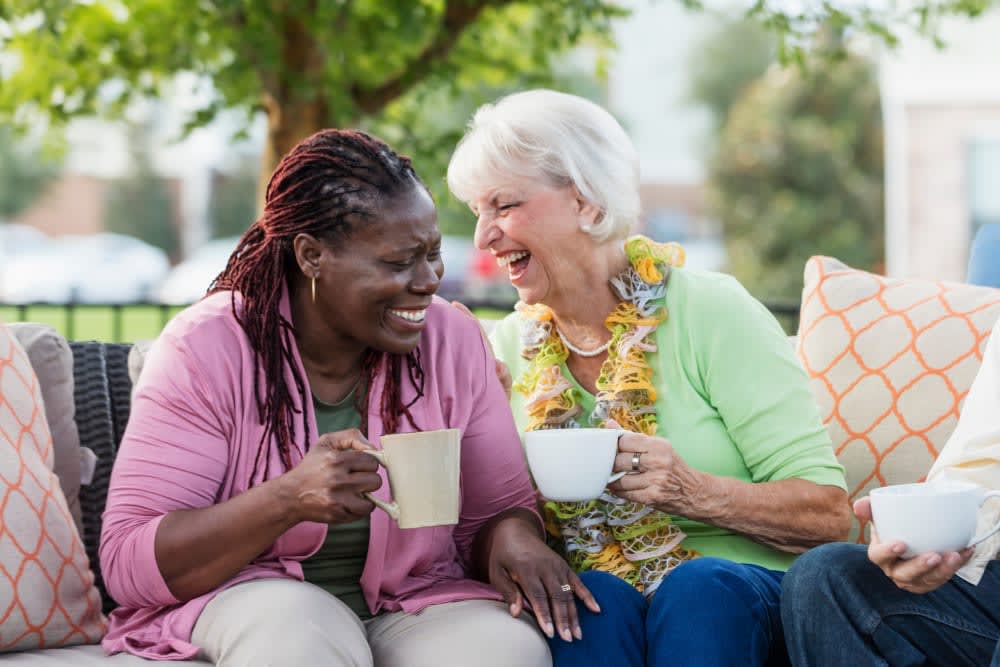 Two elderly women enjoying coffee and conversation outdoors.