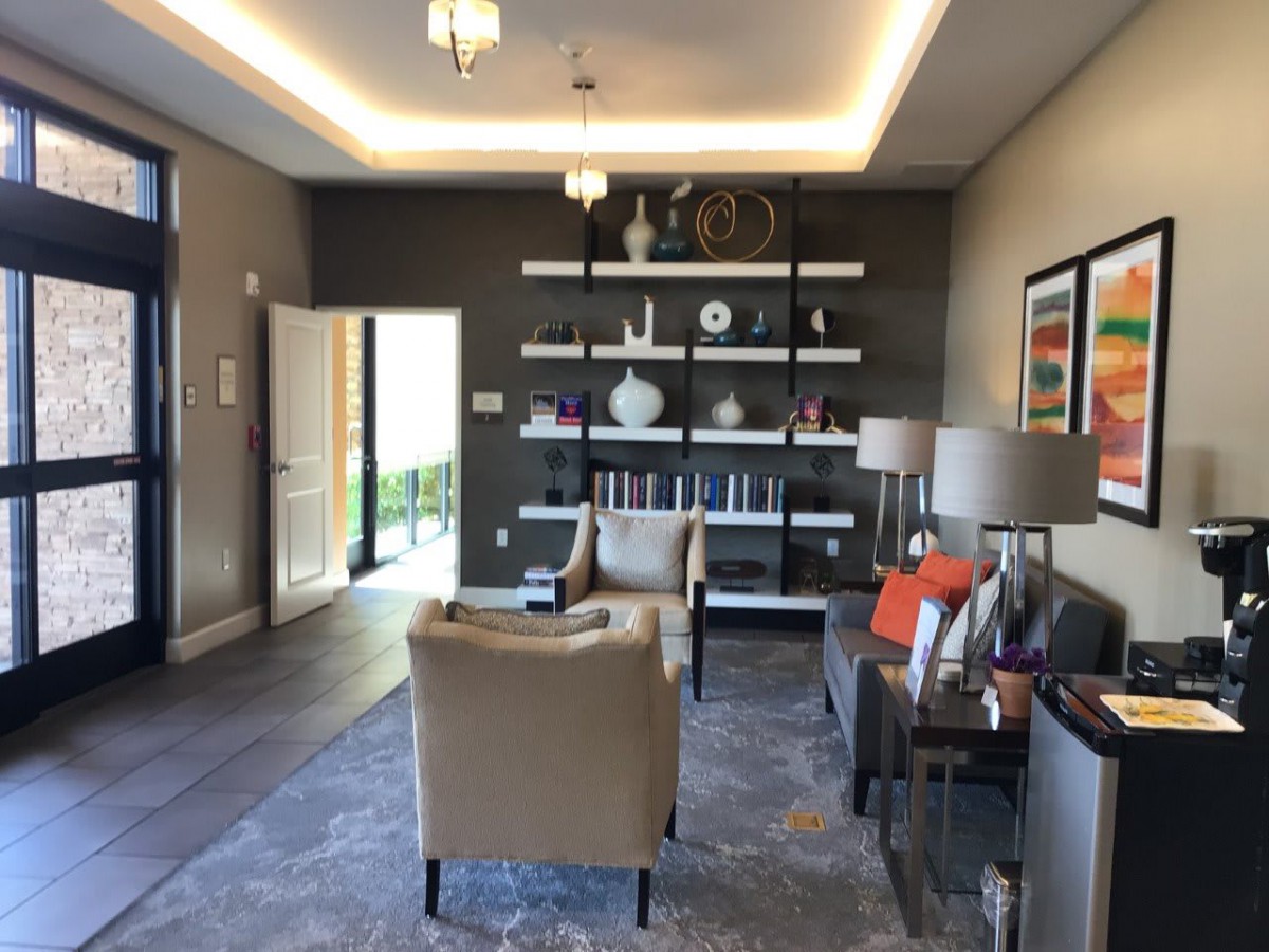A modern living room with armchairs, shelves filled with books and vases, complemented by stylish lamps.