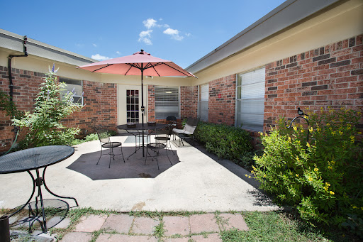 A cozy outdoor patio area featuring a bright umbrella and seating for relaxation.
