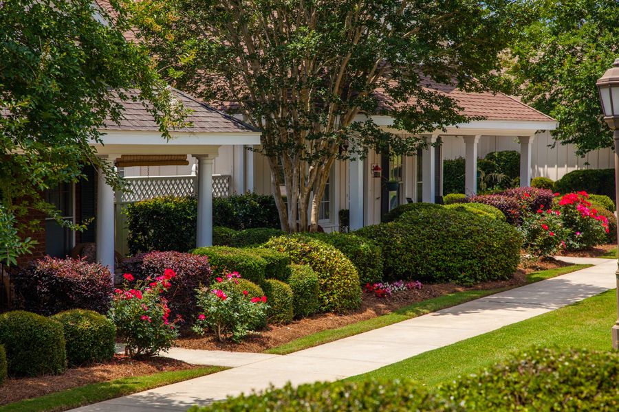 A beautifully landscaped house with a well-maintained garden and a neat sidewalk.