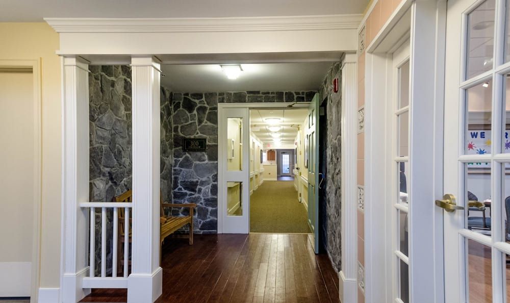 A hallway with stone walls and a wooden floor leading to a distant doorway.