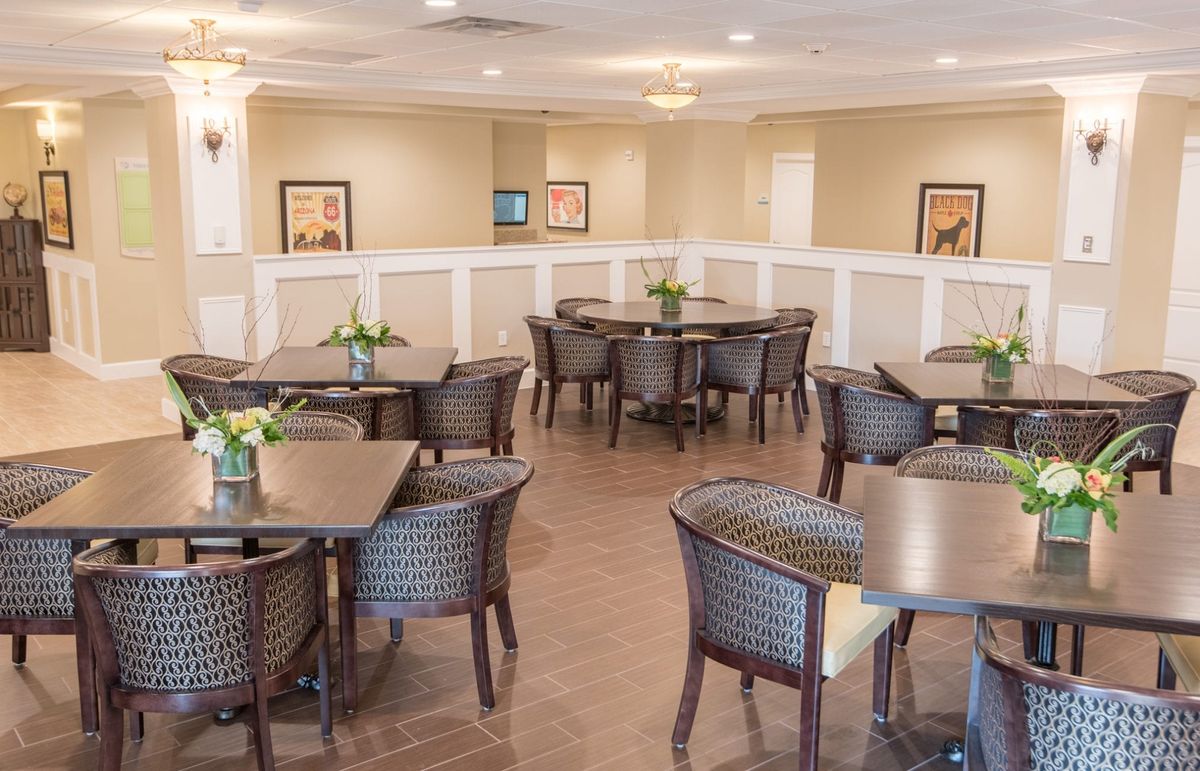 A well-lit dining area with multiple tables and chairs, adorned with small plants.