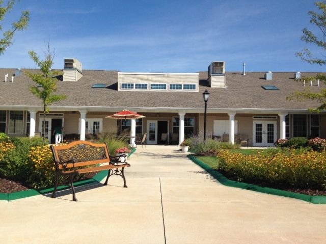 A scenic view of a building with a bench and garden in the foreground.