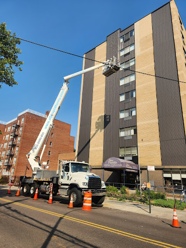 A bucket truck positioned in front of a multi-story building, used for maintenance work.