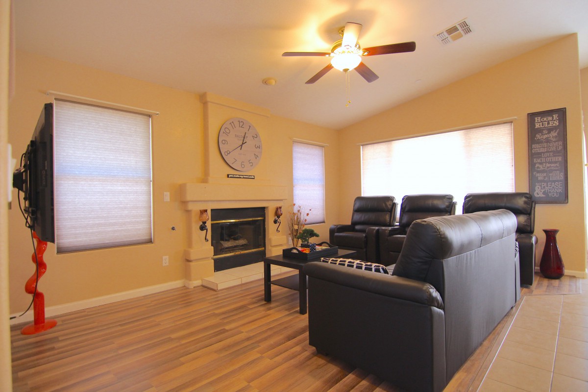 A cozy living room featuring a home theater setup with leather seating, a fireplace, and wood flooring.