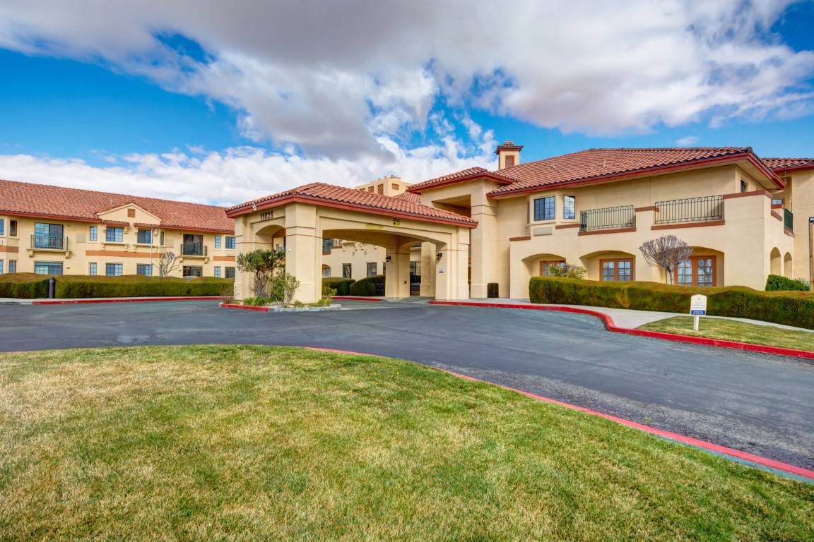 A well-maintained hotel exterior with a driveway and a cloudy sky backdrop.
