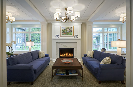 A cozy living room featuring blue sofas, a warm fireplace, and elegant lighting.