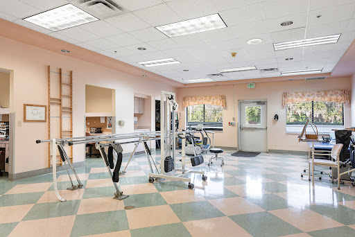 A spacious rehabilitation room equipped with exercise equipment, designed for physical therapy sessions.