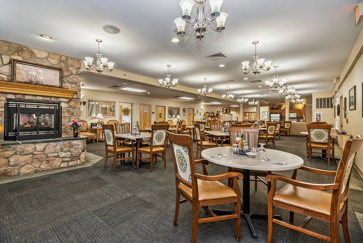A cozy dining area with elegant chandeliers, tables, and chairs arranged for guests.