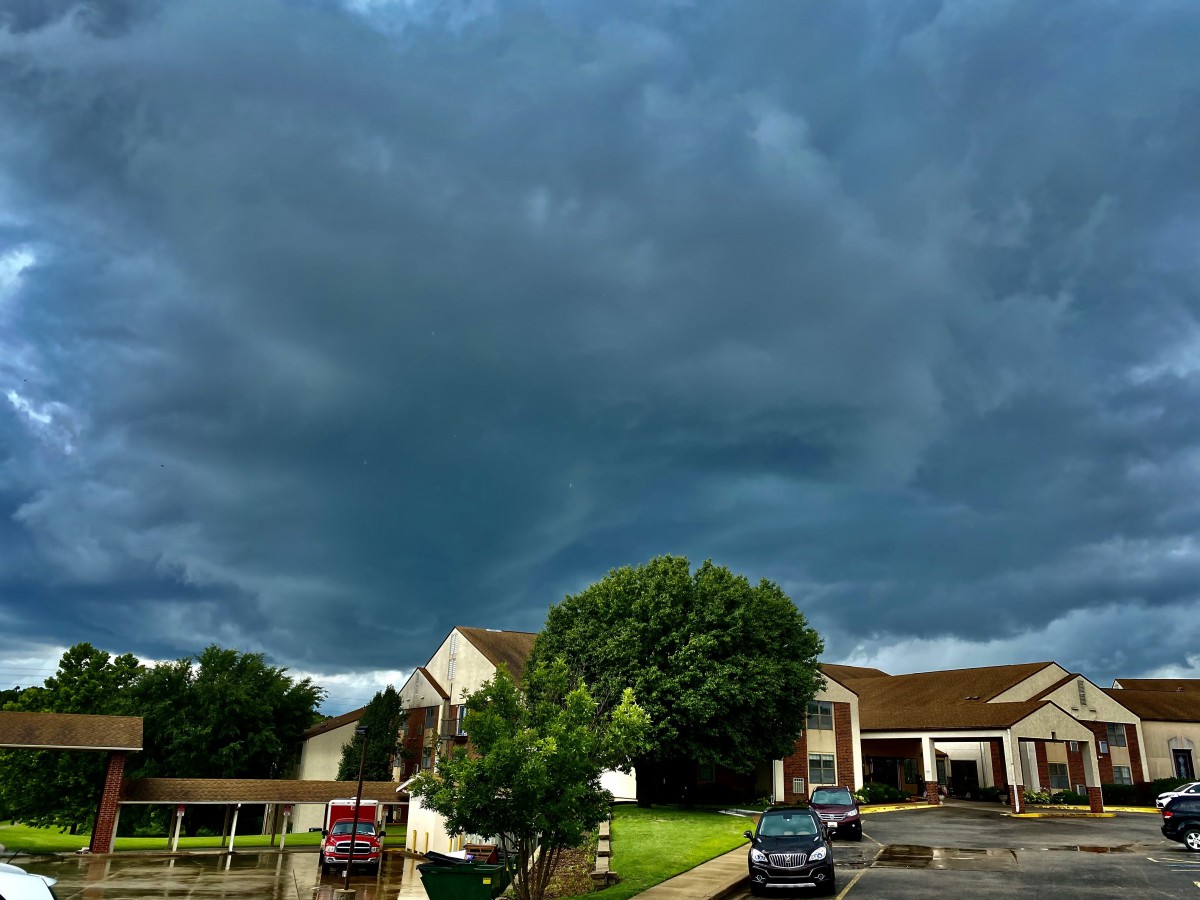 A stormy sky looms over a residential neighborhood with dark clouds gathering above.
