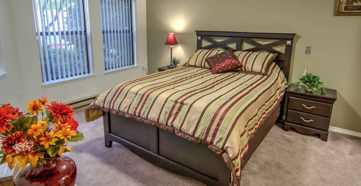 A cozy bedroom with a striped bedspread and a red pillow.