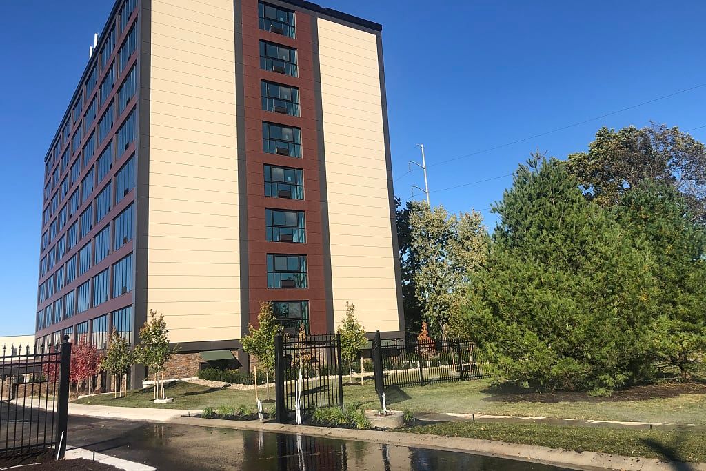 A modern office building surrounded by trees under a clear blue sky.