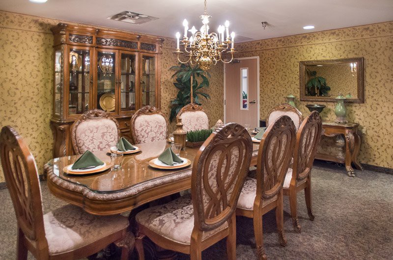 An elegant dining room with a chandelier and traditional wooden furniture, set for a meal.