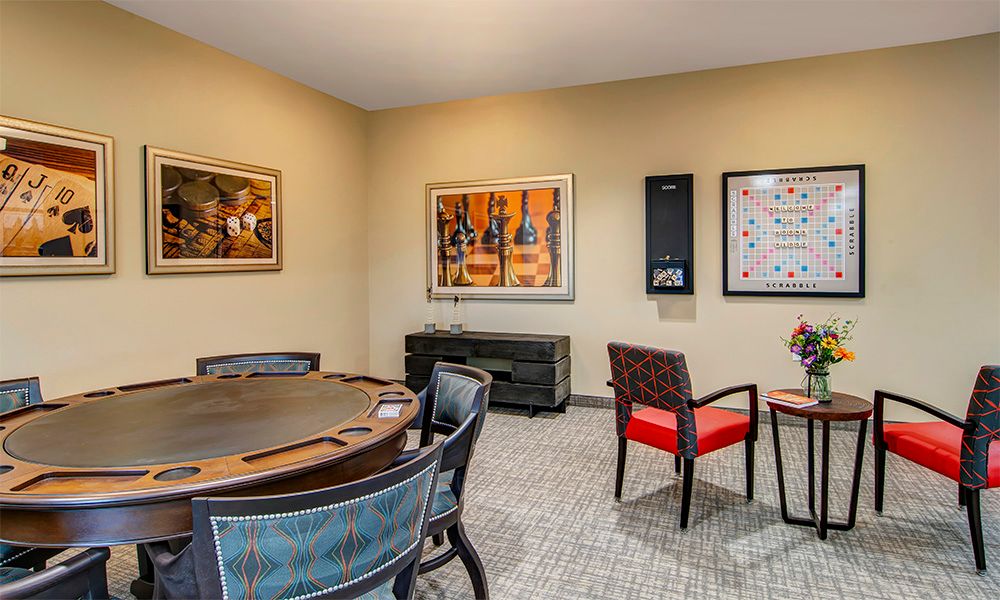 A cozy poker room featuring a large game table, comfortable chairs, and modern artwork on the walls.