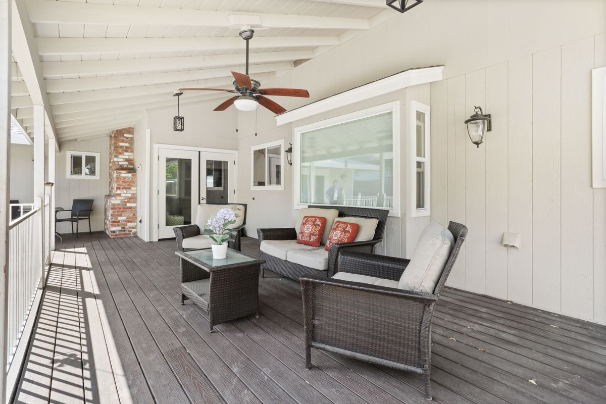 A cozy and inviting patio with wicker furniture and a ceiling fan, perfect for outdoor relaxation.