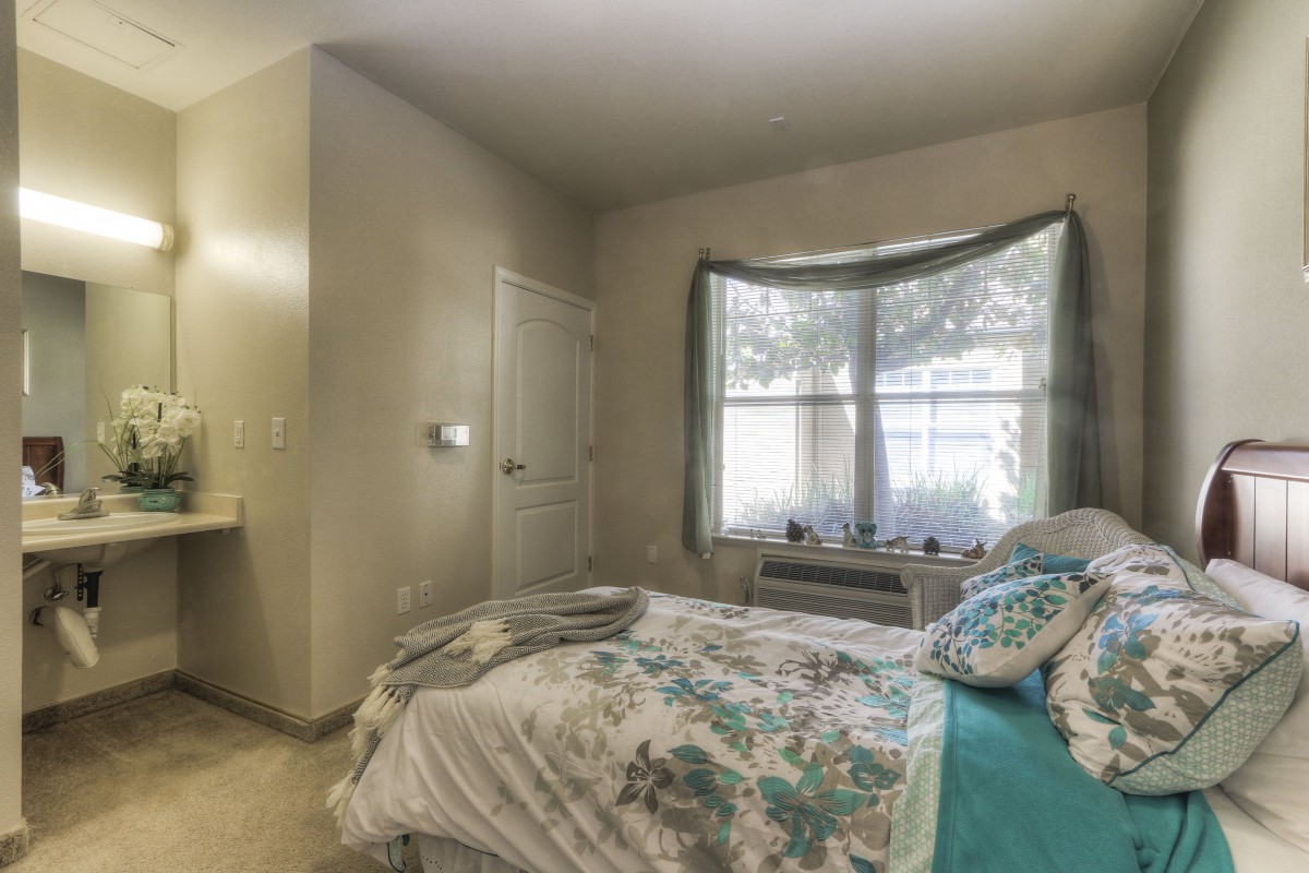 A cozy bedroom with floral bedding and a large window.