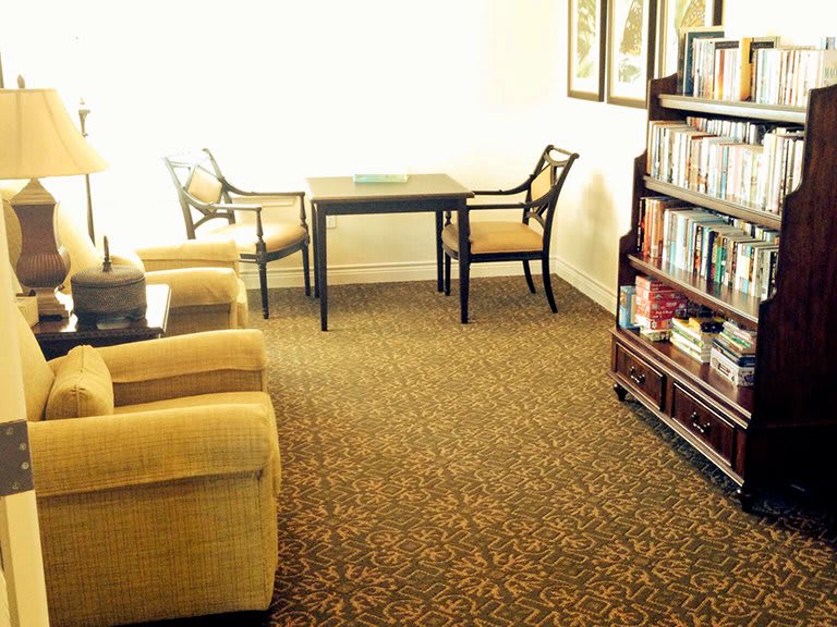 A cozy living room with a table, chairs, and a well-stocked bookshelf.