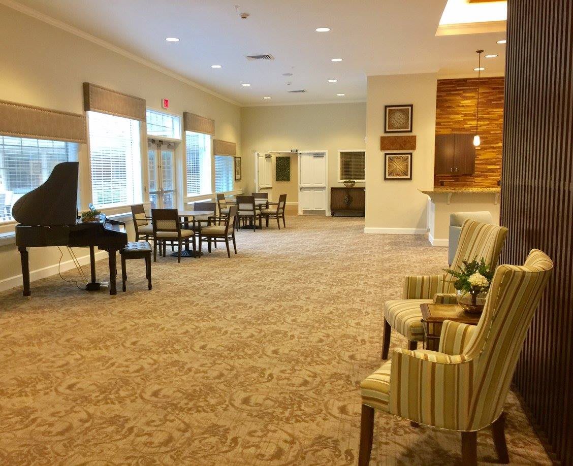 A cozy lounge area featuring a piano, seating arrangements, and large windows.