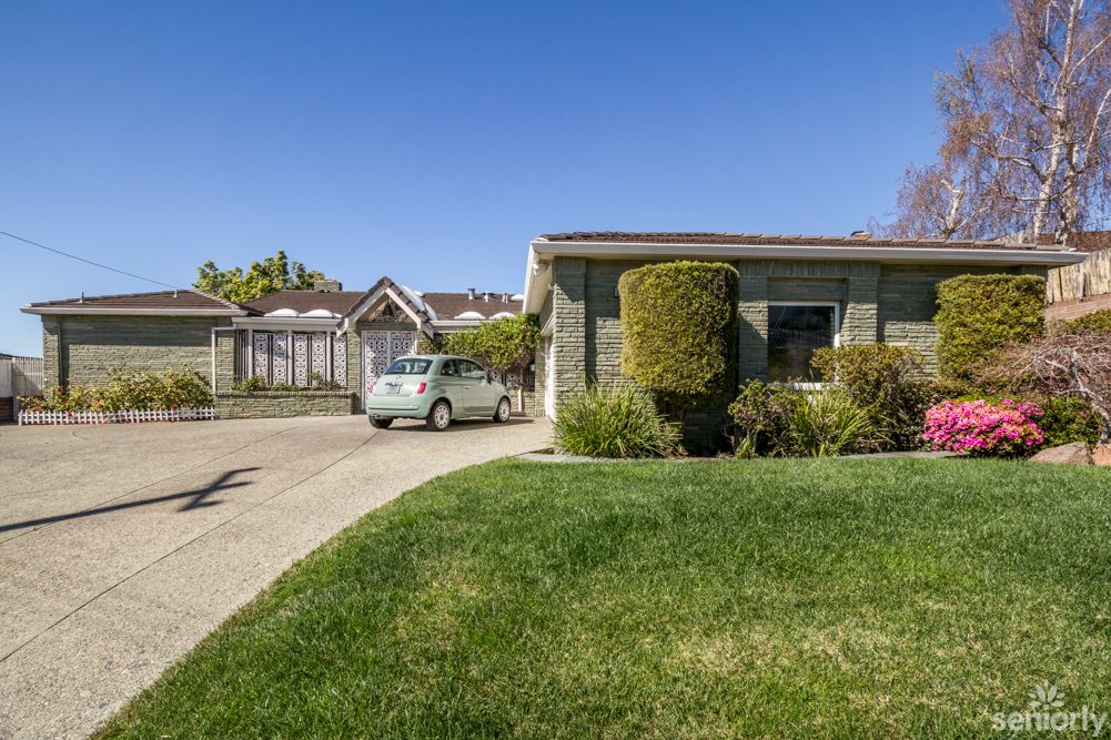 A suburban house with a driveway and a car parked on a sunny day.