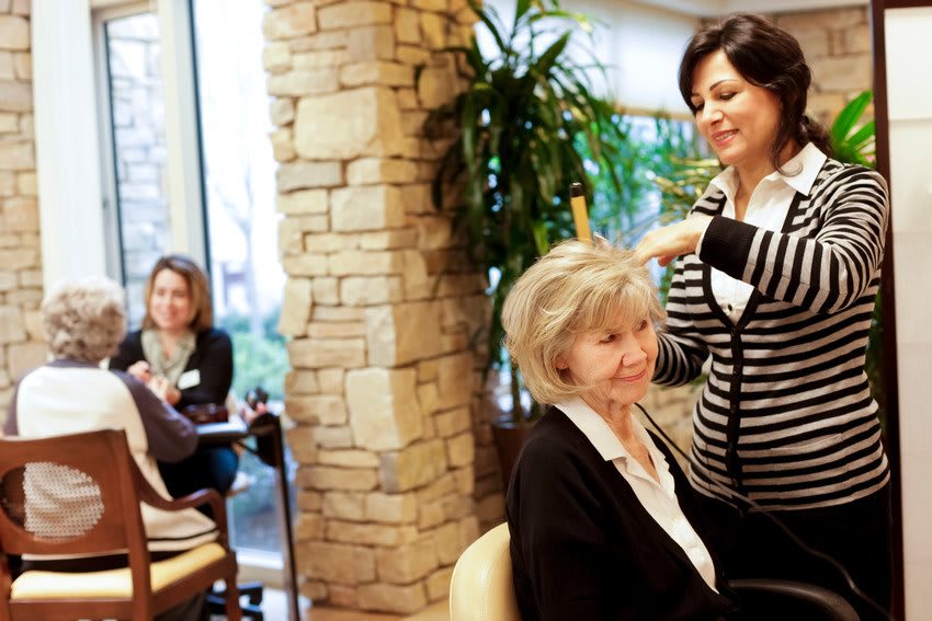 A hairdresser styles the hair of a customer in a cozy salon.