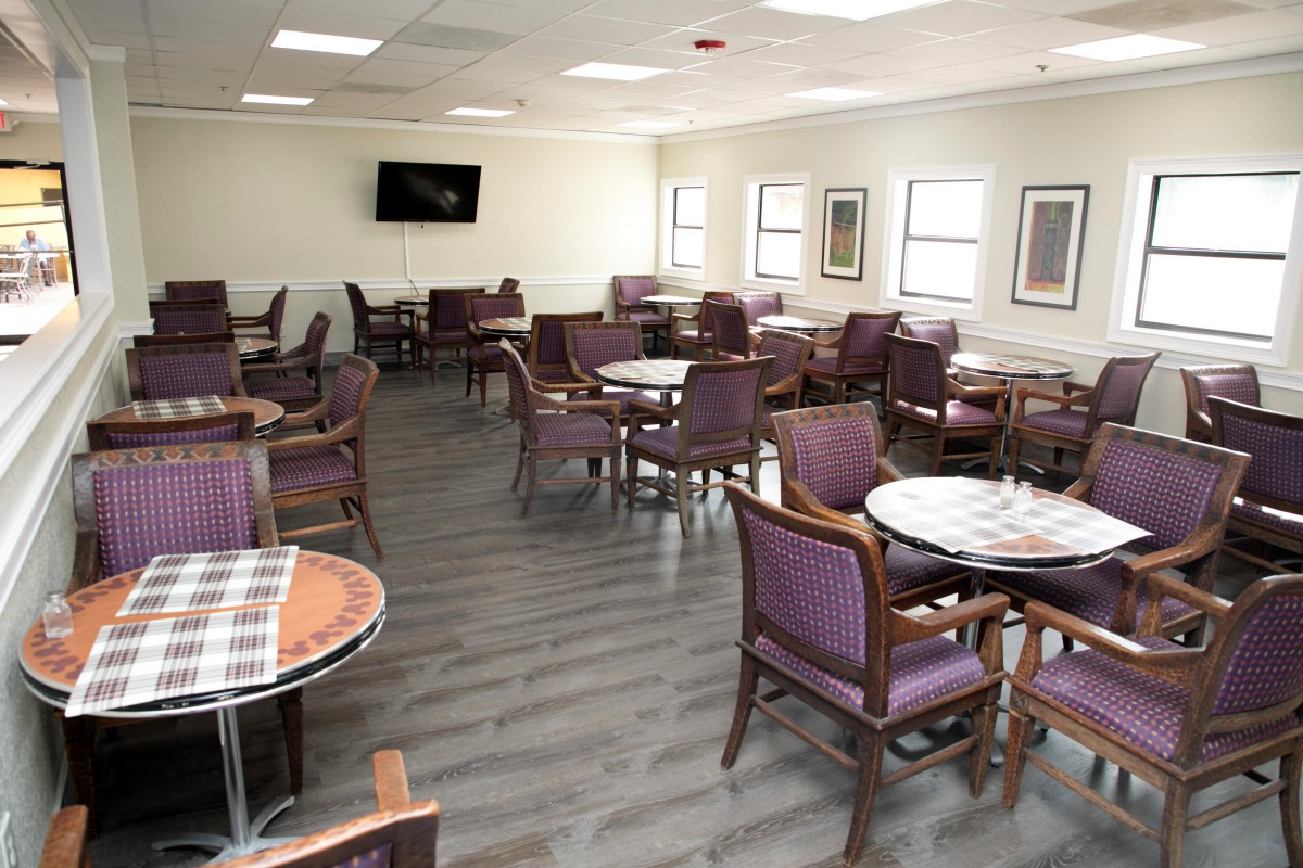 A spacious dining area with multiple tables and chairs, featuring a television on the wall.